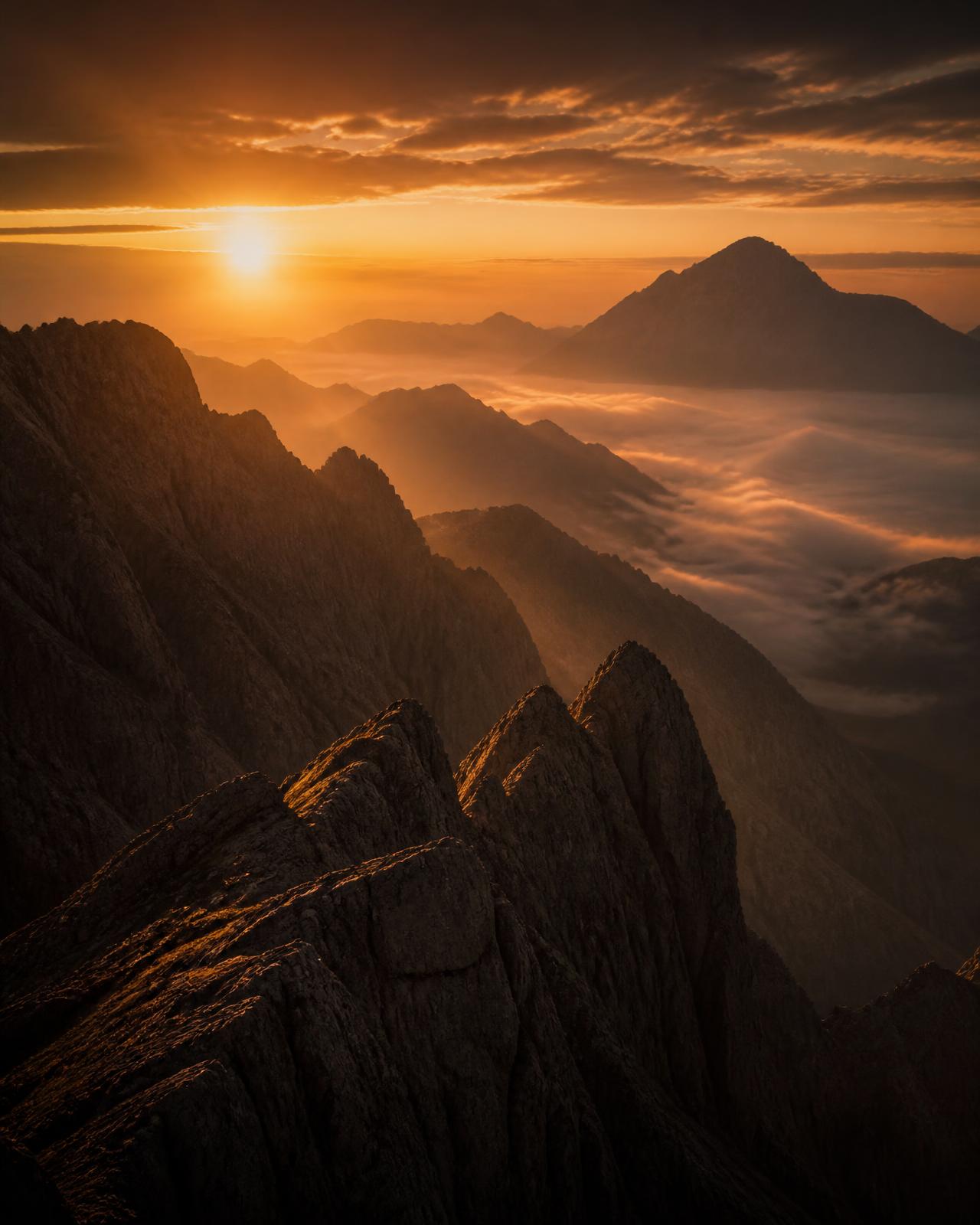 Dawn light breaking over a mountain ridge above a valley of mist